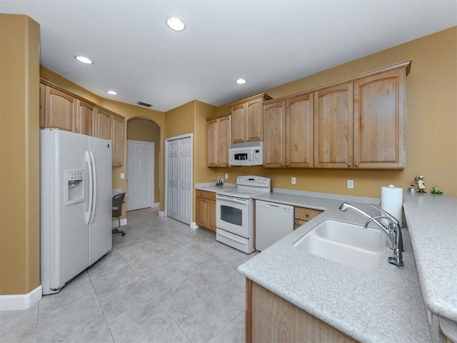 kitchen featuring arched walkways, recessed lighting, light countertops, a sink, and white appliances