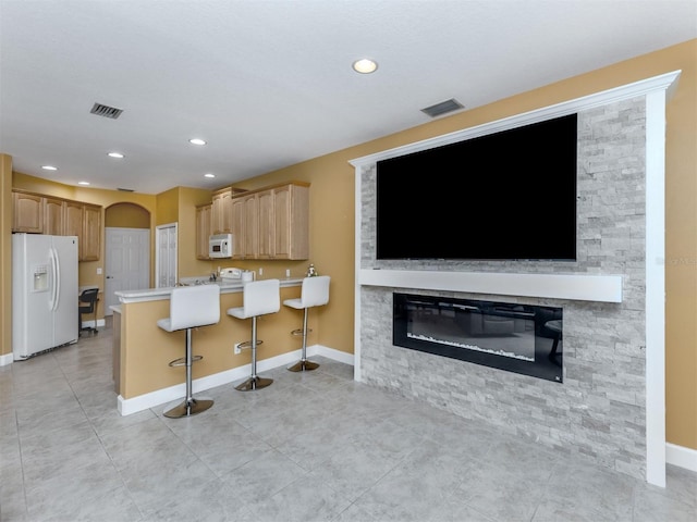 kitchen featuring white appliances, baseboards, visible vents, arched walkways, and a peninsula