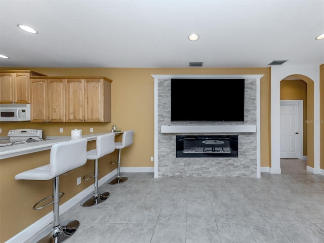 kitchen featuring arched walkways, light countertops, visible vents, stove, and white microwave