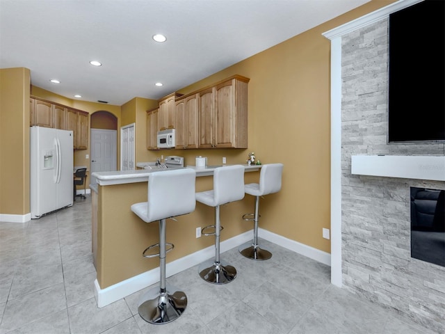 kitchen with arched walkways, light tile patterned floors, light countertops, white appliances, and a peninsula