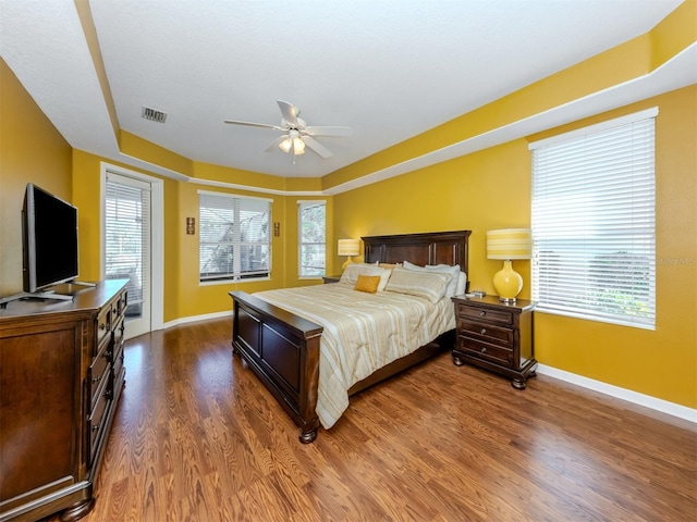 bedroom featuring wood finished floors, visible vents, baseboards, access to exterior, and a raised ceiling