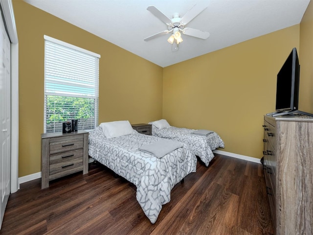 bedroom with dark wood-style floors, a ceiling fan, and baseboards