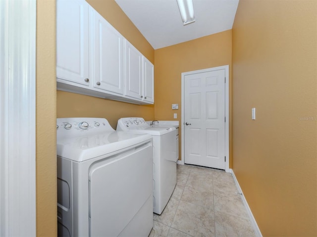 clothes washing area with baseboards, light tile patterned floors, cabinet space, and washer and dryer