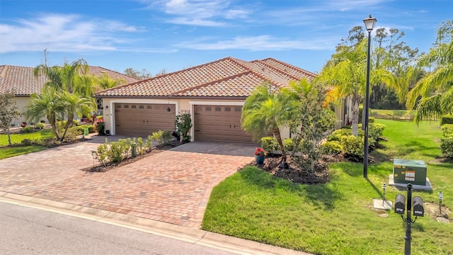 mediterranean / spanish-style home featuring a garage, a front lawn, decorative driveway, and a tiled roof