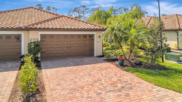 view of front of property featuring an attached garage, a tiled roof, decorative driveway, and stucco siding