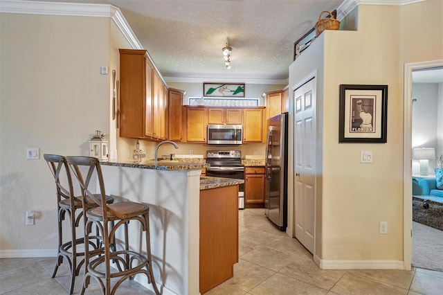 kitchen featuring appliances with stainless steel finishes, ornamental molding, a sink, a peninsula, and a kitchen breakfast bar