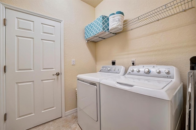 laundry room with a textured wall, light tile patterned flooring, laundry area, baseboards, and independent washer and dryer