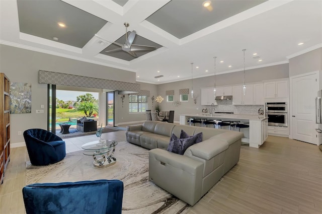 living area with ornamental molding, light wood-type flooring, coffered ceiling, and ceiling fan