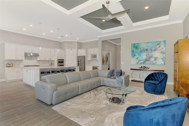 living area with a ceiling fan, light wood-type flooring, ornamental molding, and baseboards