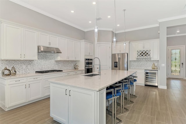 kitchen featuring beverage cooler, a breakfast bar area, appliances with stainless steel finishes, under cabinet range hood, and a sink