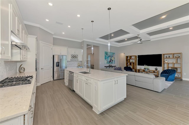 kitchen featuring under cabinet range hood, stainless steel appliances, a sink, white cabinets, and open floor plan