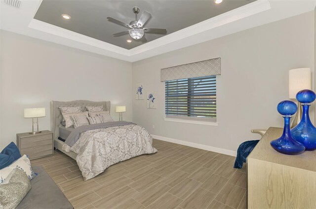 bedroom with wood tiled floor, a raised ceiling, visible vents, and baseboards