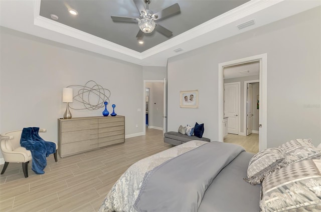 bedroom with visible vents, baseboards, ornamental molding, a tray ceiling, and light wood finished floors