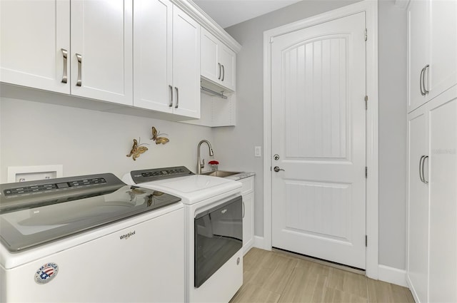 laundry area with a sink, washing machine and dryer, cabinet space, and baseboards