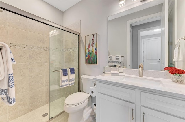 bathroom with a tile shower, vanity, and toilet