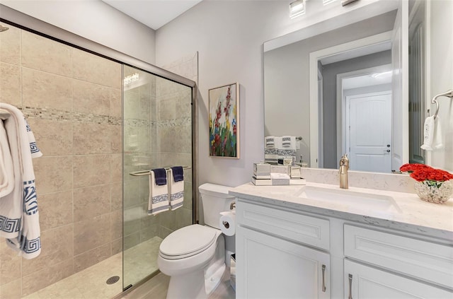 bathroom featuring a shower stall, toilet, and vanity