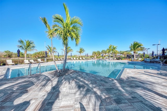 community pool with a patio area and fence