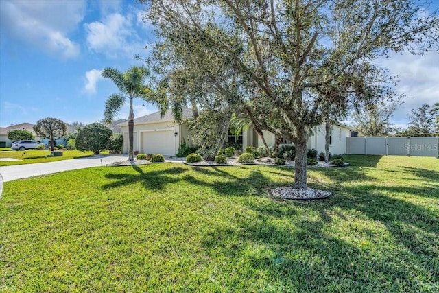 view of front facade with stucco siding, concrete driveway, an attached garage, a front yard, and fence