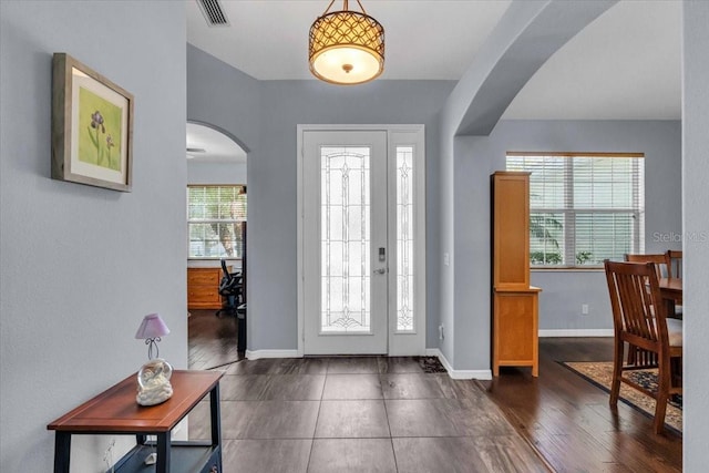 entryway featuring arched walkways, visible vents, baseboards, and wood finished floors