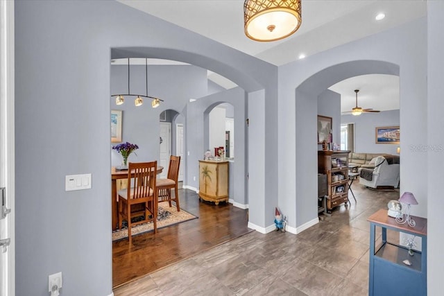 hall featuring arched walkways, baseboards, and recessed lighting