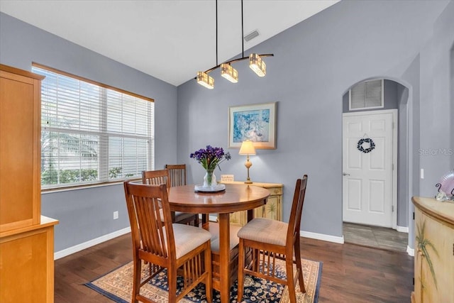 dining room featuring dark wood-style floors, arched walkways, visible vents, and vaulted ceiling