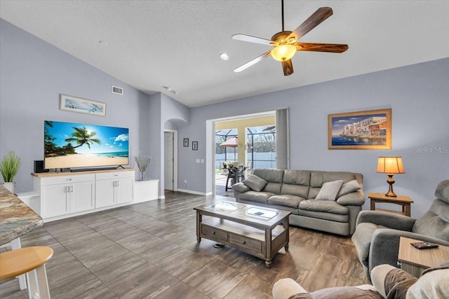 living area featuring visible vents, arched walkways, a ceiling fan, a textured ceiling, and high vaulted ceiling