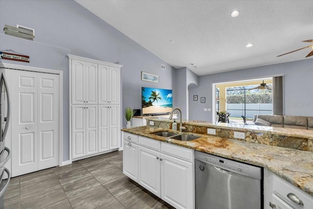 kitchen with white cabinets, ceiling fan, vaulted ceiling, stainless steel dishwasher, and a sink