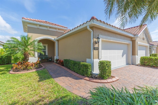 view of front of property with a garage, a tile roof, decorative driveway, stucco siding, and a front lawn