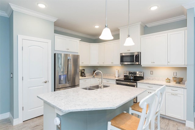 kitchen with a breakfast bar, crown molding, appliances with stainless steel finishes, light wood-style floors, and a sink