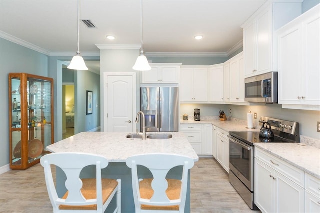 kitchen featuring light wood finished floors, visible vents, appliances with stainless steel finishes, white cabinets, and a sink