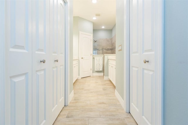 corridor with light wood-type flooring, baseboards, and recessed lighting