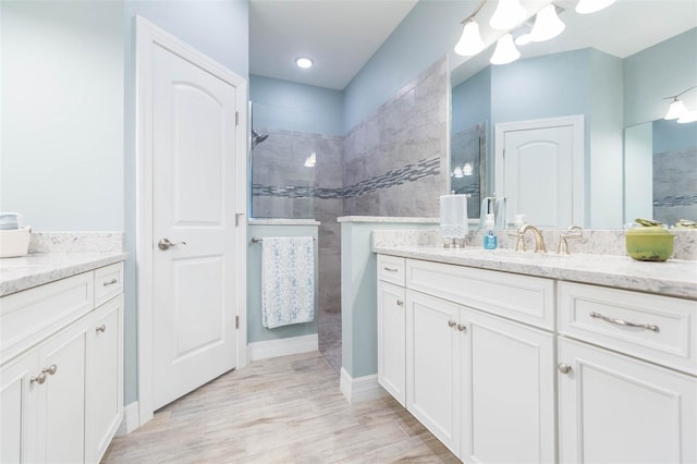 bathroom with wood finished floors, walk in shower, and vanity