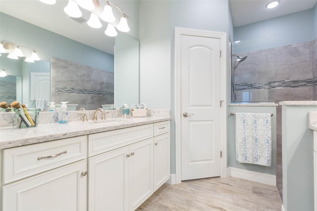 bathroom with wood finished floors, a notable chandelier, vanity, and a walk in shower