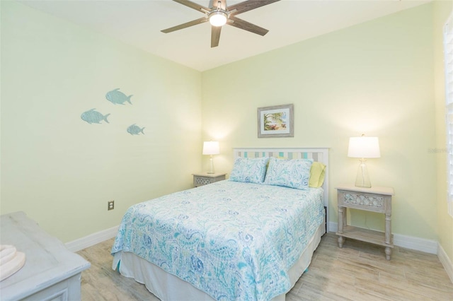 bedroom with light wood finished floors, a ceiling fan, and baseboards