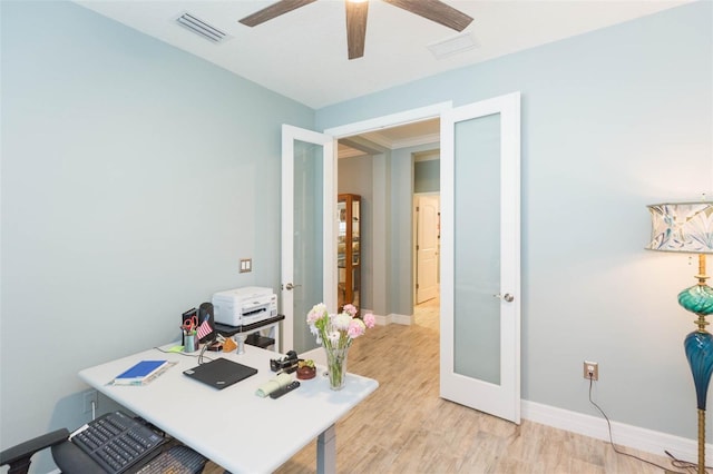 home office featuring light wood-style flooring, a ceiling fan, visible vents, and baseboards