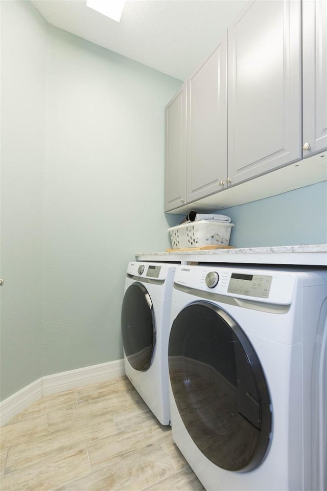 washroom featuring baseboards, light wood-style floors, cabinet space, and washer and dryer