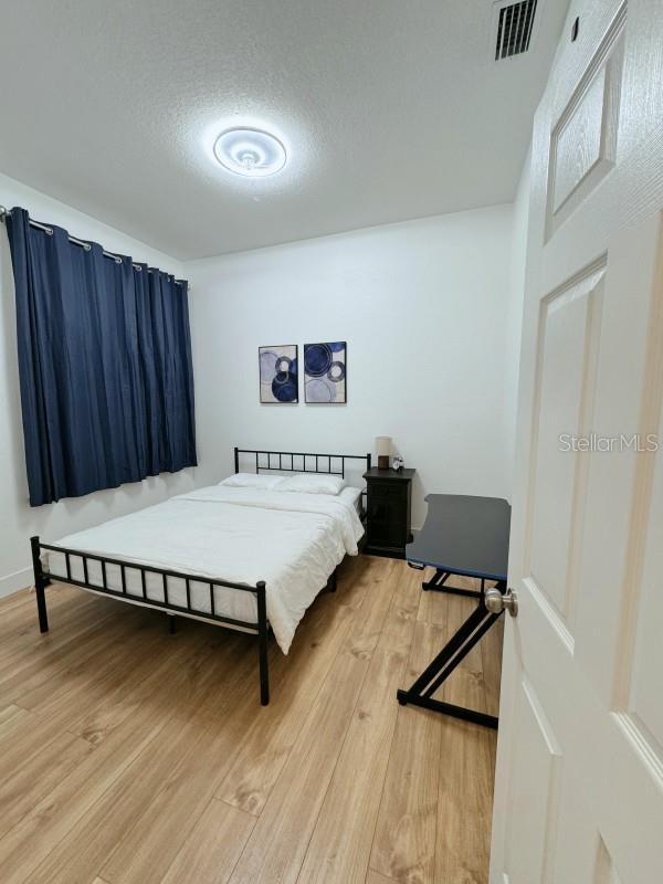 bedroom featuring a textured ceiling, light wood-style flooring, and visible vents