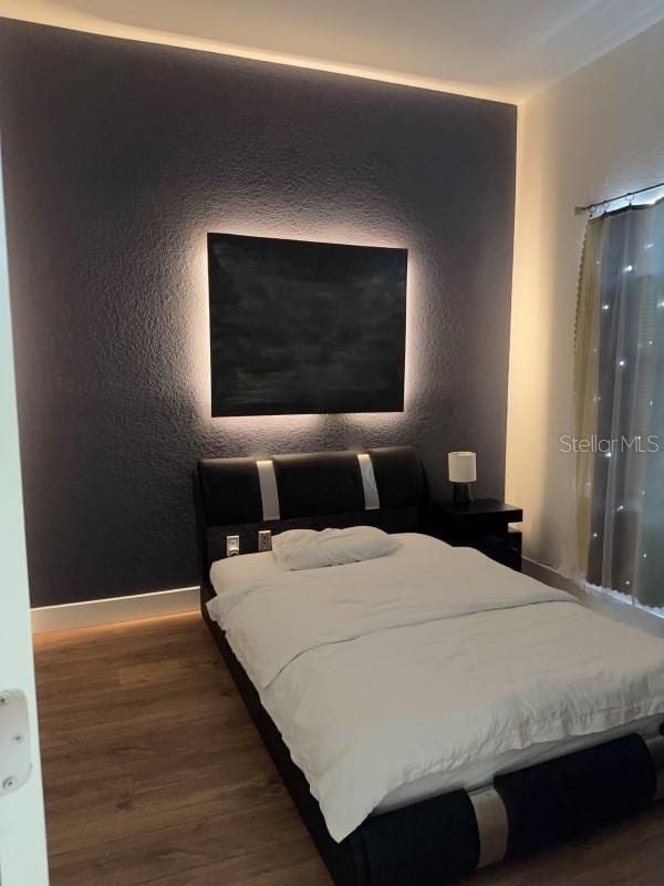 bedroom featuring wood finished floors and baseboards