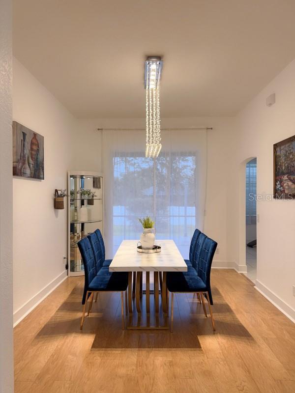 3650 S Sumter Blvd, North Port, FL 34287 - dining space featuring light wood-style flooring, arched walkways, and baseboards