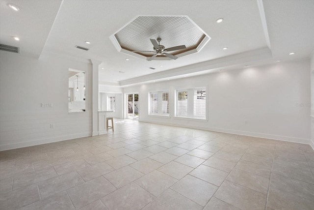 unfurnished living room featuring light tile patterned floors, visible vents, a ceiling fan, and a tray ceiling