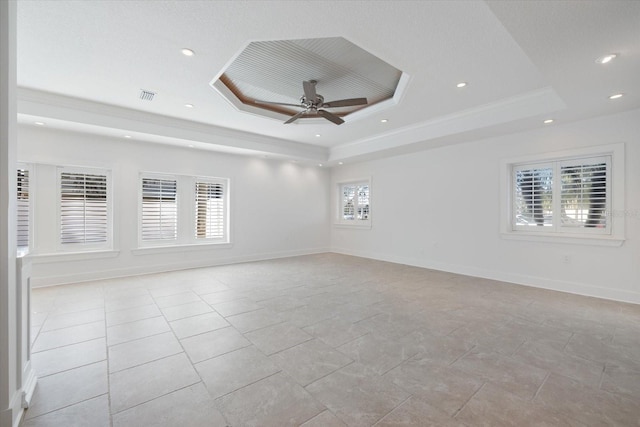 spare room featuring visible vents, ornamental molding, a ceiling fan, baseboards, and a raised ceiling