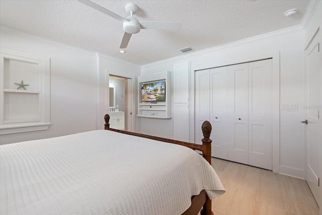 bedroom with a textured ceiling, a closet, crown molding, light wood finished floors, and ceiling fan