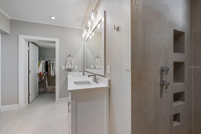 full bath featuring a sink, baseboards, a textured ceiling, and double vanity