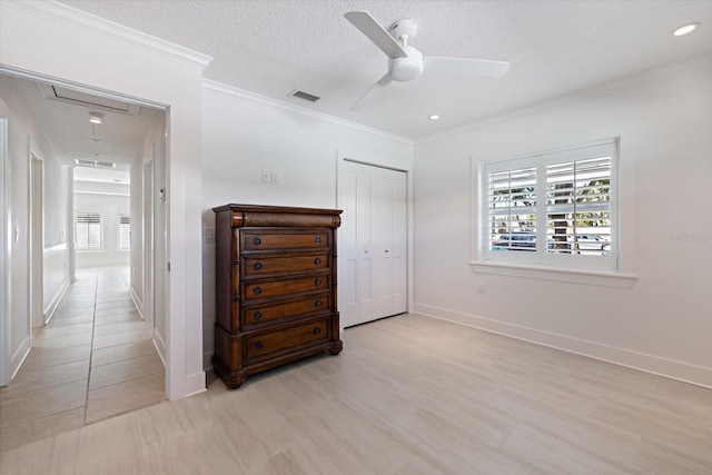 bedroom with visible vents, attic access, ornamental molding, a textured ceiling, and multiple windows