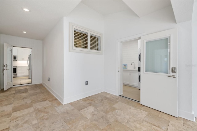 hallway featuring recessed lighting, baseboards, and stacked washer / dryer