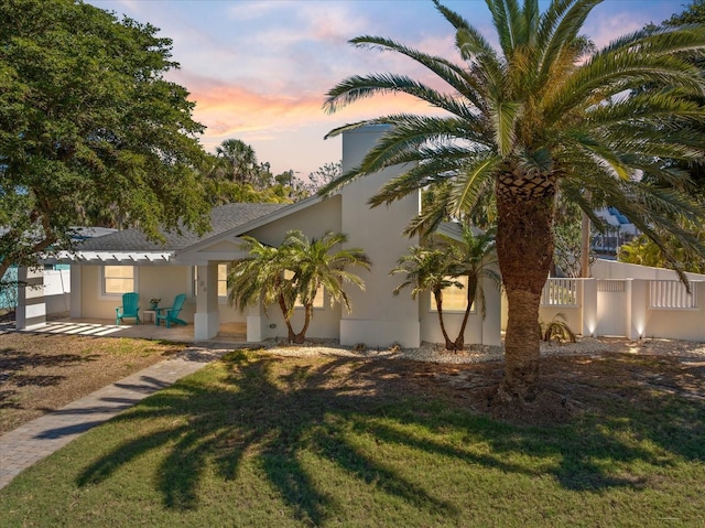 view of front of property featuring stucco siding, a front yard, and fence