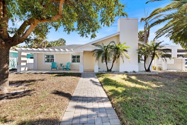 view of front of property with stucco siding, a patio, and a front yard