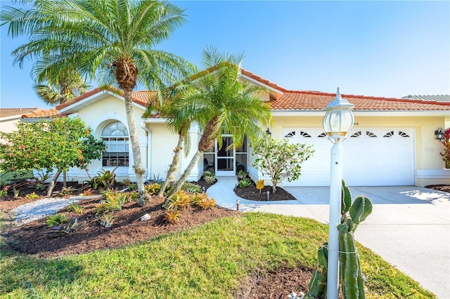 mediterranean / spanish-style home with a garage, concrete driveway, a tile roof, and stucco siding