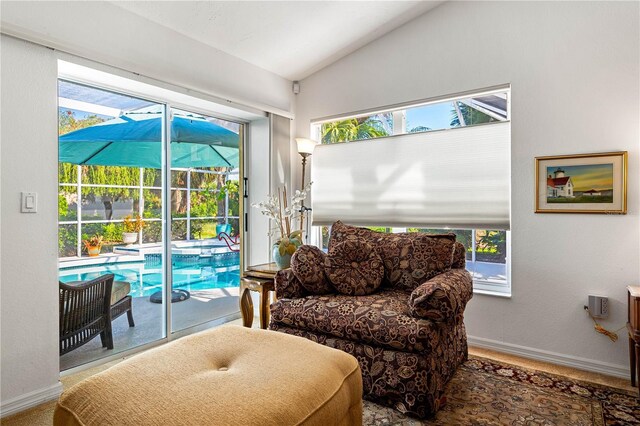 living area with lofted ceiling, a healthy amount of sunlight, baseboards, and a sunroom