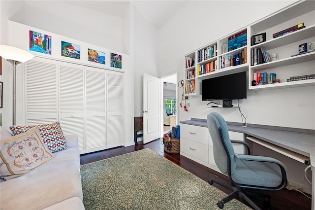 office with a towering ceiling and dark wood-style floors